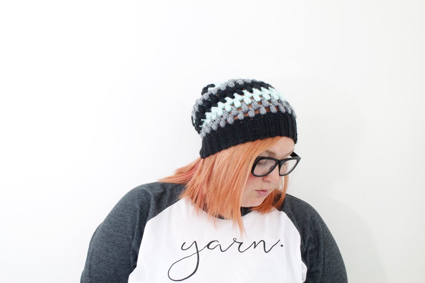 multicolor puff stitch beanie in black dark gray and mint on model with peach hair and black glasses