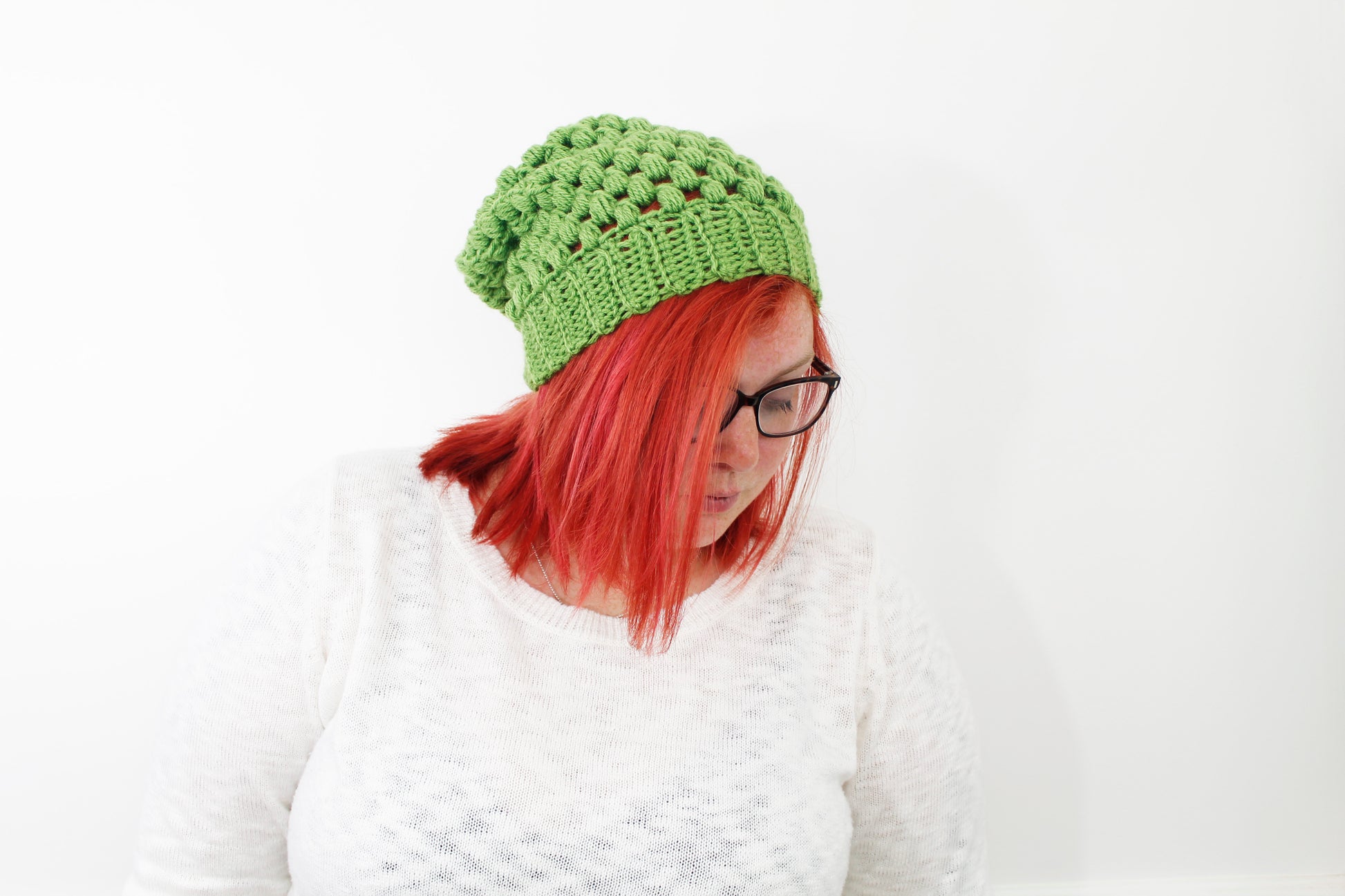 puff stitch beanie in grass green color on model with neon red hair and black glasses