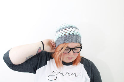 puff stitch beanie in white light gray and mint stripes on model with peach hair and black glasses