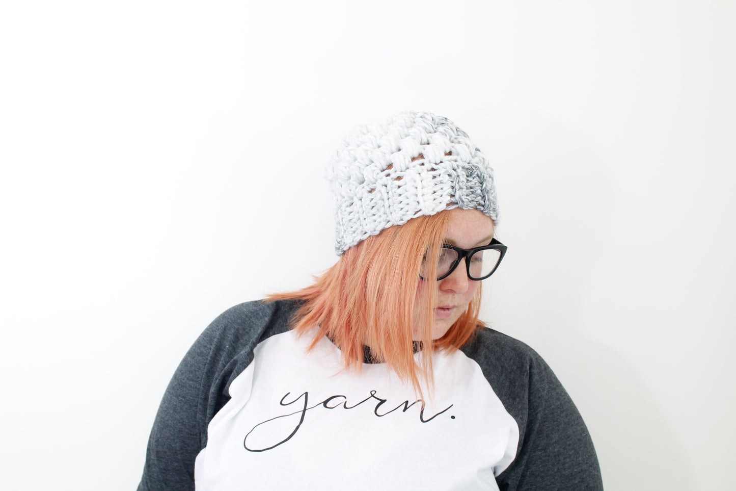 chunky puff stitch beanie in variegated shades of white and gray on model with black glasses and peach hair